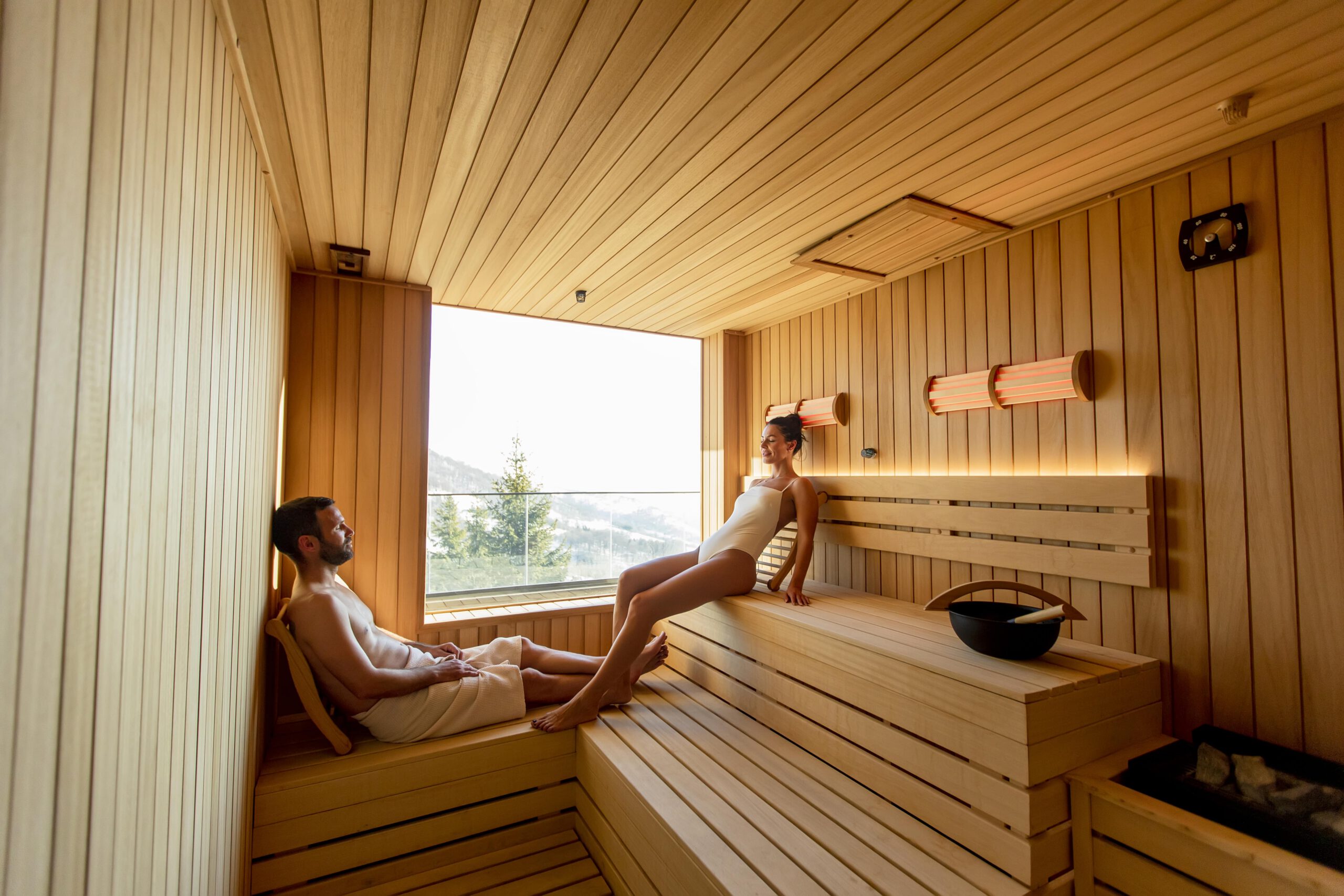 Sauna traditionnel, infrarouge, hammam,… : quelles différences ? 2 young couple relaxing in the sauna and watching wi 2025 02 22 16 06 23 utc min scaled